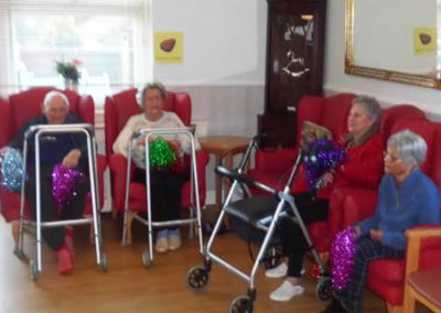 A group of Woodstock residents seated around the edge of their lounge, enjoying an exercise class together