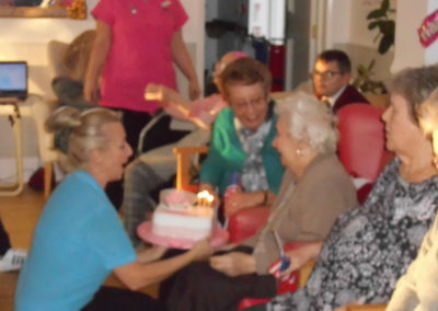 Resident Lily blowing out candles on her birthday cake at Woodstock Residential Care Home