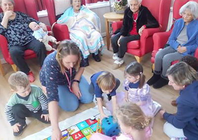 Nursery children playing giant floor snakes and ladders at Woodstock Residential Care Home