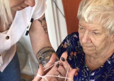 Lady resident playing a game of cats cradle with a staff member 3