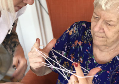 Lady resident playing a game of cats cradle with a staff member 5