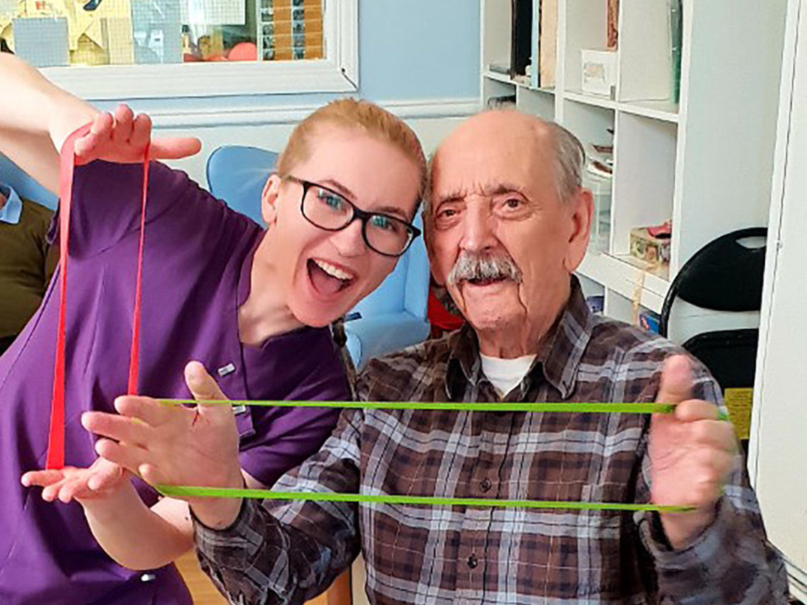 Resident and staff member stretching resistance bands together
