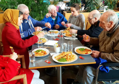 A group of Lukestone residents and staff from Lukestone sat around a table eating fish and chips ar Dobbies Garden Centre