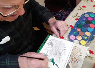 Male resident sitting at a table painting a flower picture