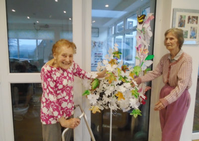 Two lady residents standing proudly by their Dignity Tree sculpture
