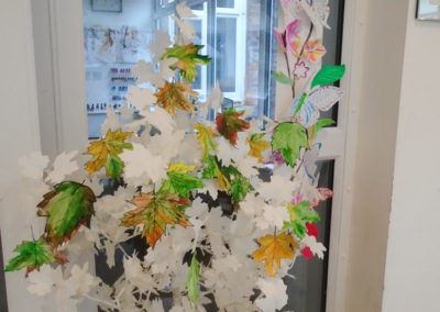 A tree sculpture made from painted tree branches and decorated with paper butterflies and leaves