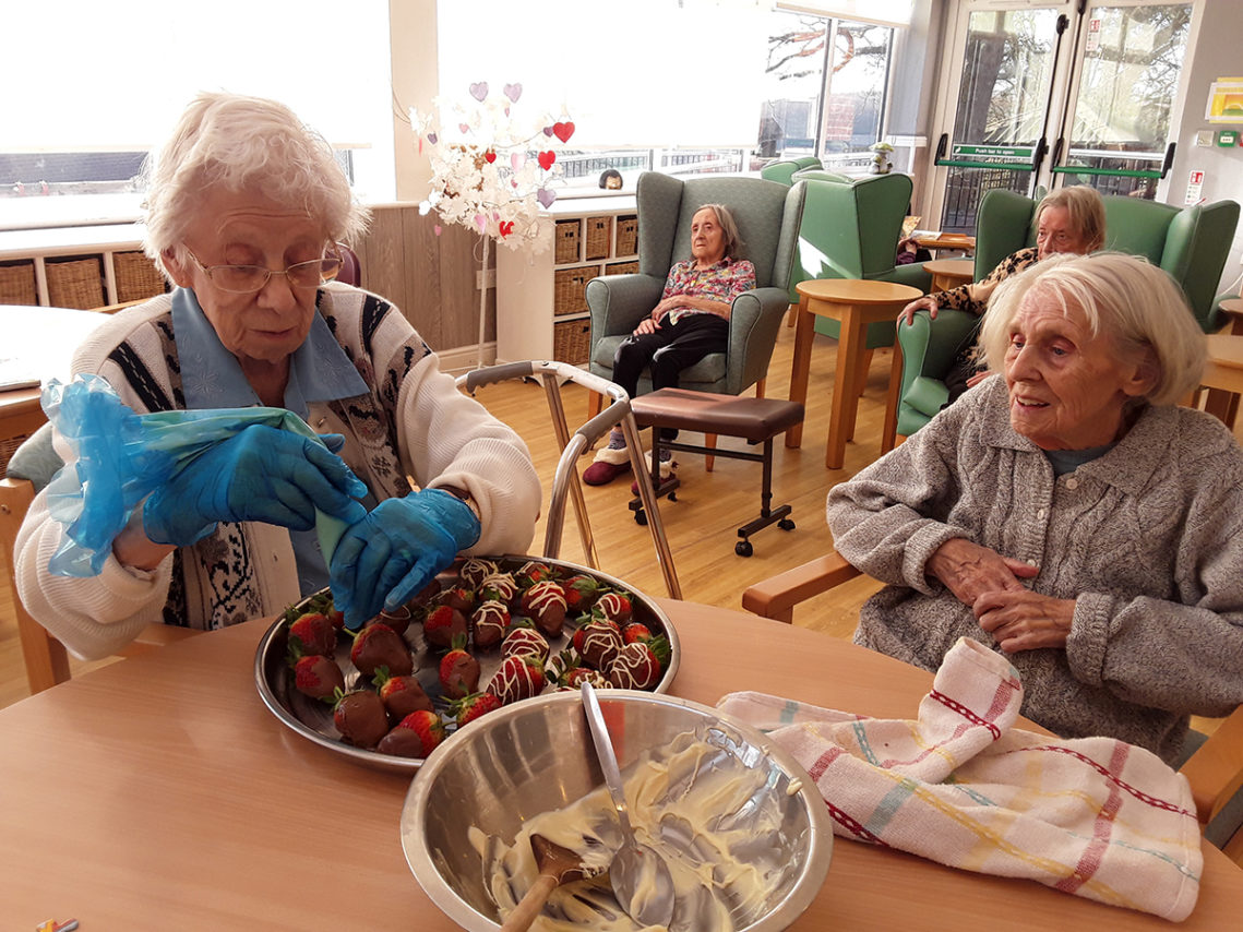 Resident decorating fresh strawberries with milk and white chocolate
