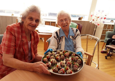 Residents showing off a tray of fresh strawberries decorated with milk and white chocolate