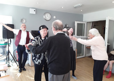 A group of residents dancing together in their lounge to live music