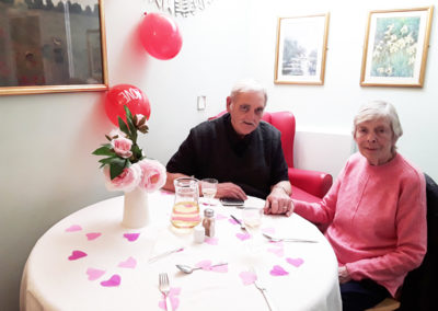 Couple sitting at a table decorated for Valentines Day, awaiting a couples lunch