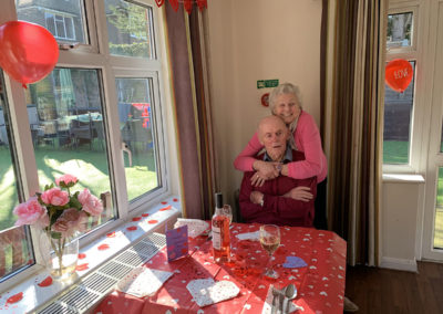 Couple cuddling together at a lunch table ready for a special Valentines meal