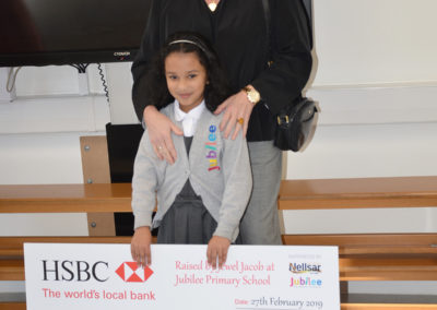School girl posing with Nellsar's Director of Operations and a large fundraising cheque