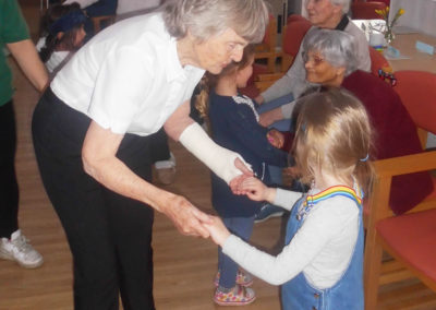 Residents and children dancing together in the lounge at Woodstock Residential Care Home