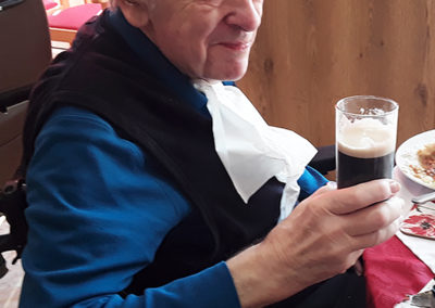 Seated resident enjoying a glass of Guinness to celebrate St Patrick's day