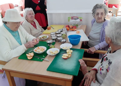 Residents sitting at a table preparing fruit salad for everyone