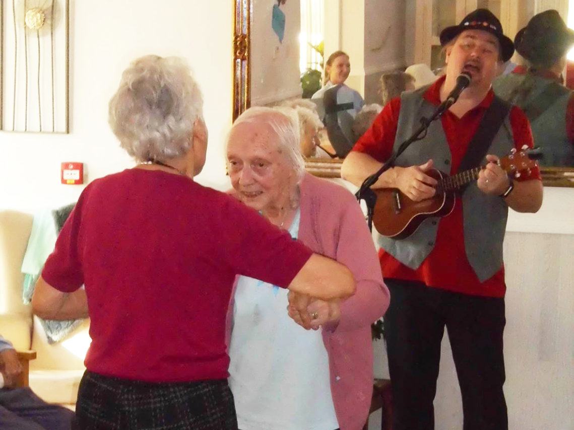 Two lady residents dancing as entertainer Rob T plays music and sings