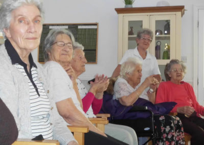 Lady residents at Woodstock Residential Care Home seated and enjoying Rob T's music in their lounge together