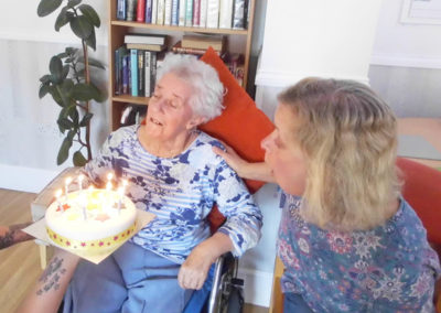 Lady resident receiving her birthday cake with candles at Woodstock Residential Care Home