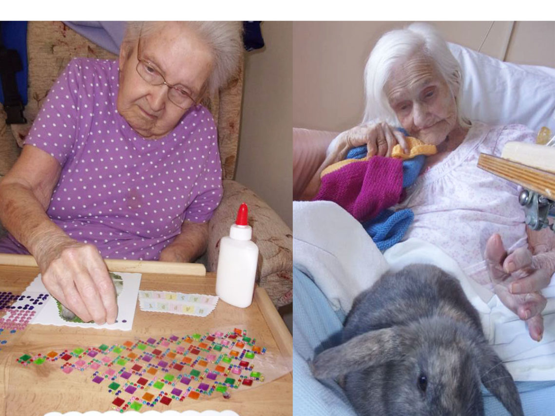Lady residents at Loose Valley, one making a card and the other cuddling a rabbit