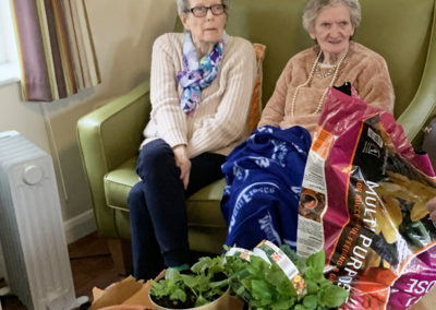 Two lady residents sitting with some gardening pots and supplies
