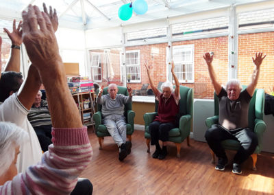 Residents stretching their arms up high during a musical gym session together at Princess Christian Care Home