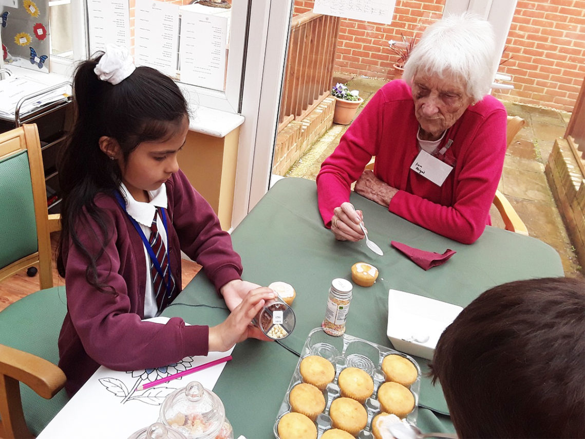 Lady resident and child decorating cakes together at Princess Christian Care Home