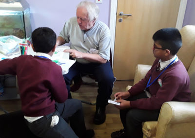 Male resident at Princess Christian Care Home doing arts and crafts with two visiting children