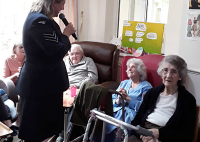 Singer in services uniform singing to resident with a microphone