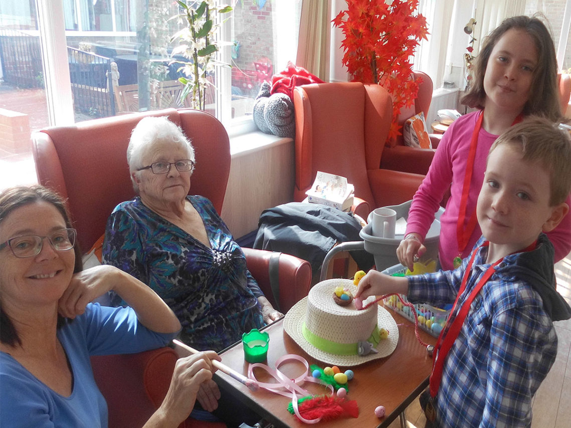 Residents and visiting children making Easter bonnets together
