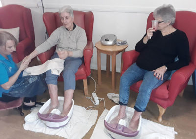 Two lady residents sitting together with their feet in foot spas