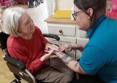 Woodstock staff member giving a lady resident a relaxing hand massage
