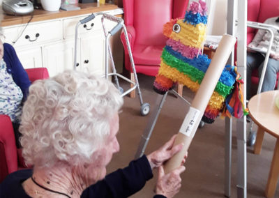 Lady resident hitting a colourful piñata with a stick