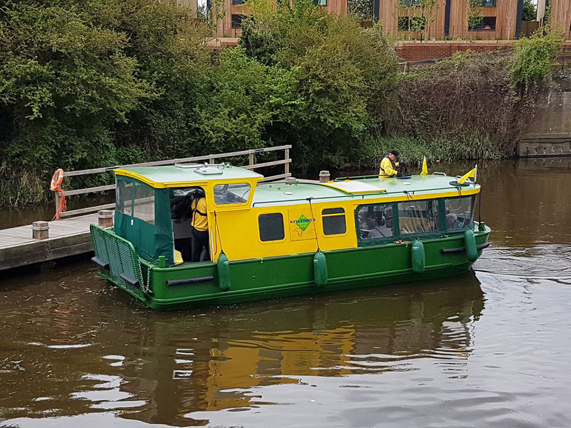 A green and yellow boat called the Kingfisher, sitting on the river Medway