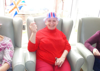 Lady resident at Sonya Lodge waving a Union Jack flag and wearing a Union Jack hat