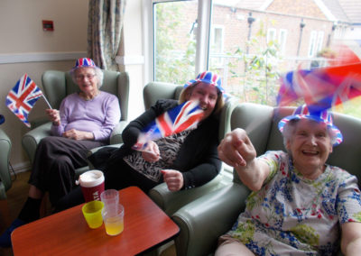Lady residents smiling and waving Union Jack flags