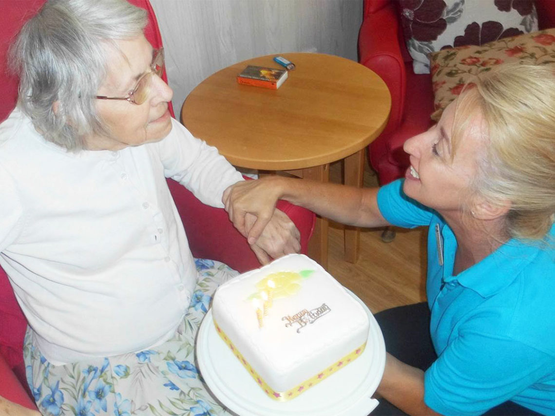 Lady resident at Meyer House Care Home receiving an iced birthday cake