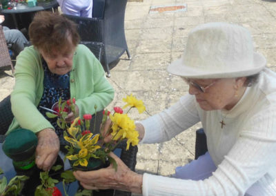 Two lady Woodstock residents arranging flowers at a table together outside in the garden