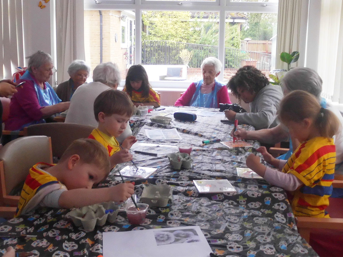 Woodstock residents and children from Little Squirrels Nursery sat around a table painting tiles together