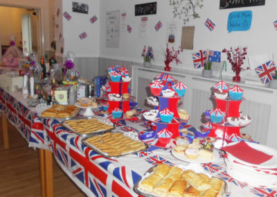 A table packed with cakes and savoury pastries, with VE Day decorations