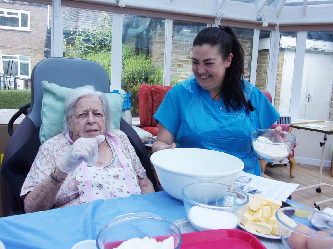 Resident and staff member mixing cake ingredients