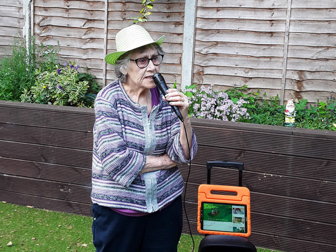 Lady resident doing karaoke in the garden at Lulworth House Residential Care Home