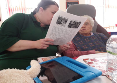 Lady resident and staff member reading a reminiscence newspaper together