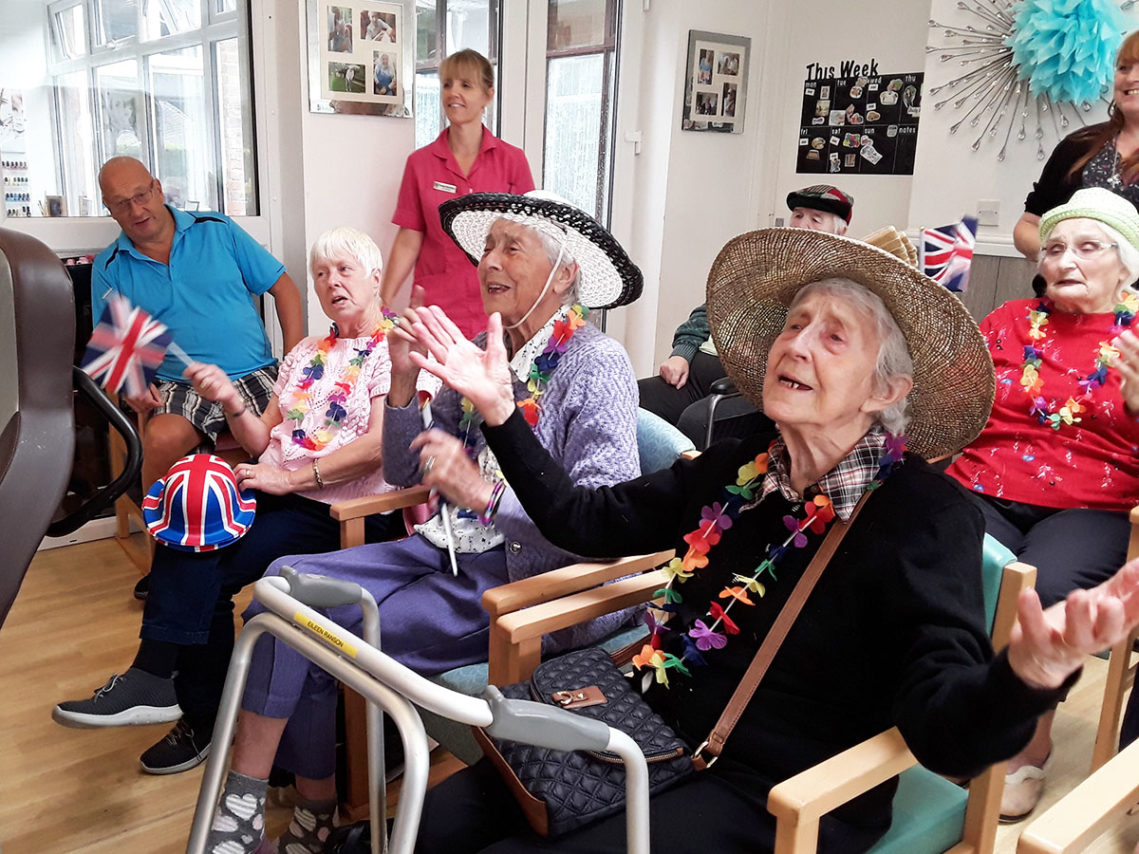 Seated residents enjoying a sing along, wearing hats and garlands
