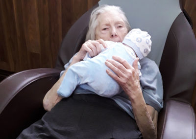 Lady resident at The Old Downs Residential Care Home cuddling with a therapy doll