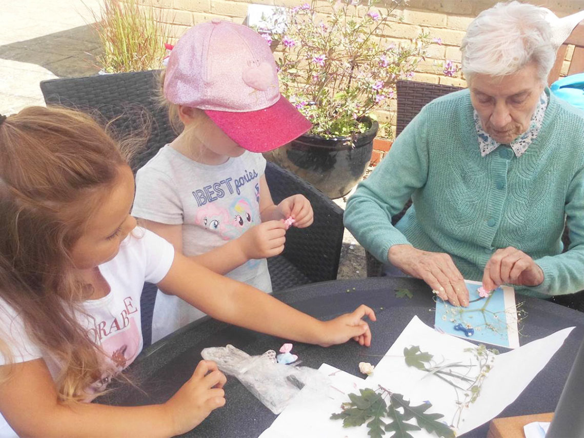 Resident with two pre-school children doing crafts in the garden