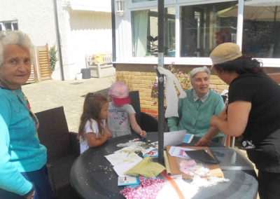 Residents and pre-school children doing arts and crafts at a table in the garden
