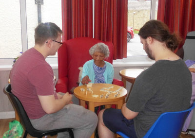 Volunteers playing dominoes with a resident at Woodstock Residential Care Home