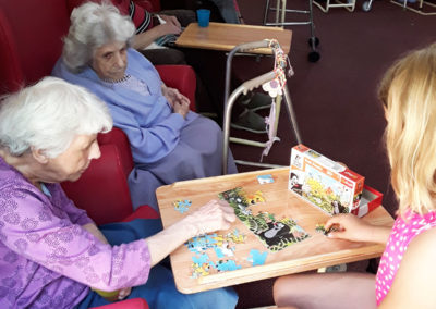 Residents enjoying doing a jigsaw puzzle together around a table at Lulworth House