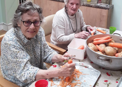 Two lady residents peeling carrots and potatoes at Lulworth House