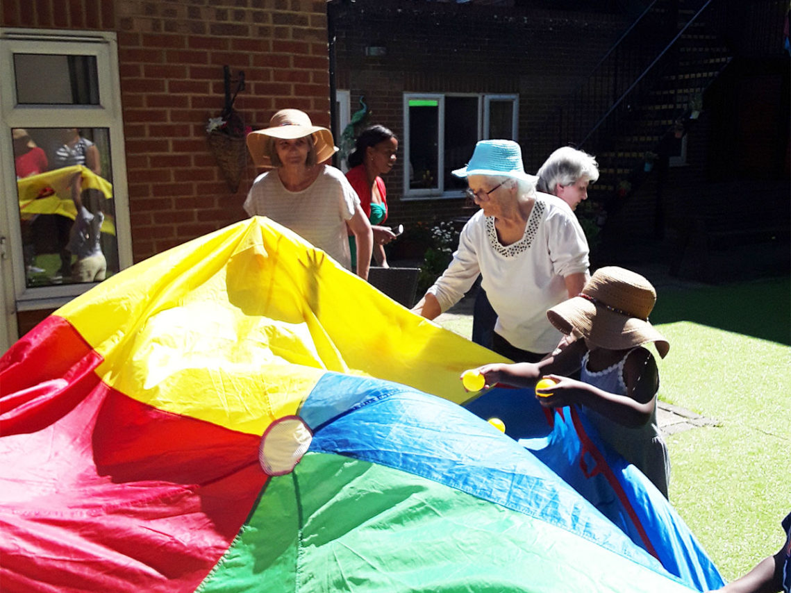 Residents and children playing parachute games Iin the garden at Lulworth House